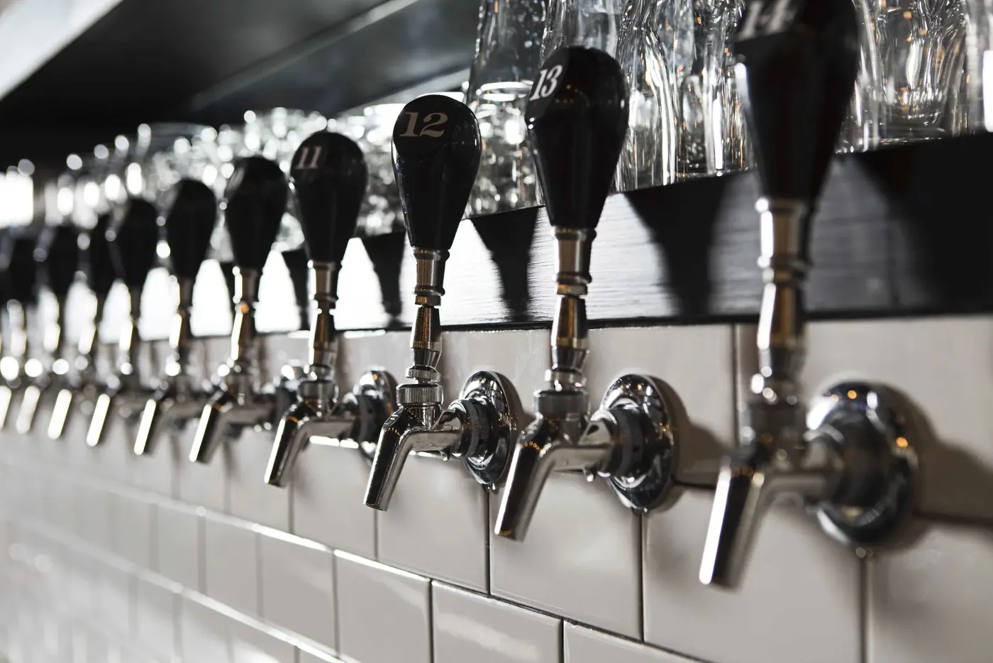 A row of draft taps against white subway tile